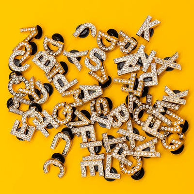 Decorative letters shoe charms with rhinestones on a yellow background
