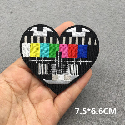 Heart-shaped patch with test pattern design held in hand on a gray background