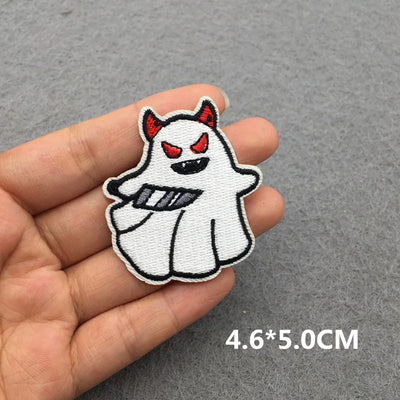 Embroidered patch of a ghost with red horns held between fingers on a gray background