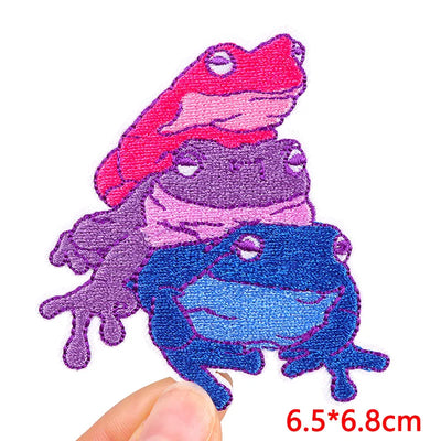 Colorful frog-shaped patch held by a hand with dimensions displayed.