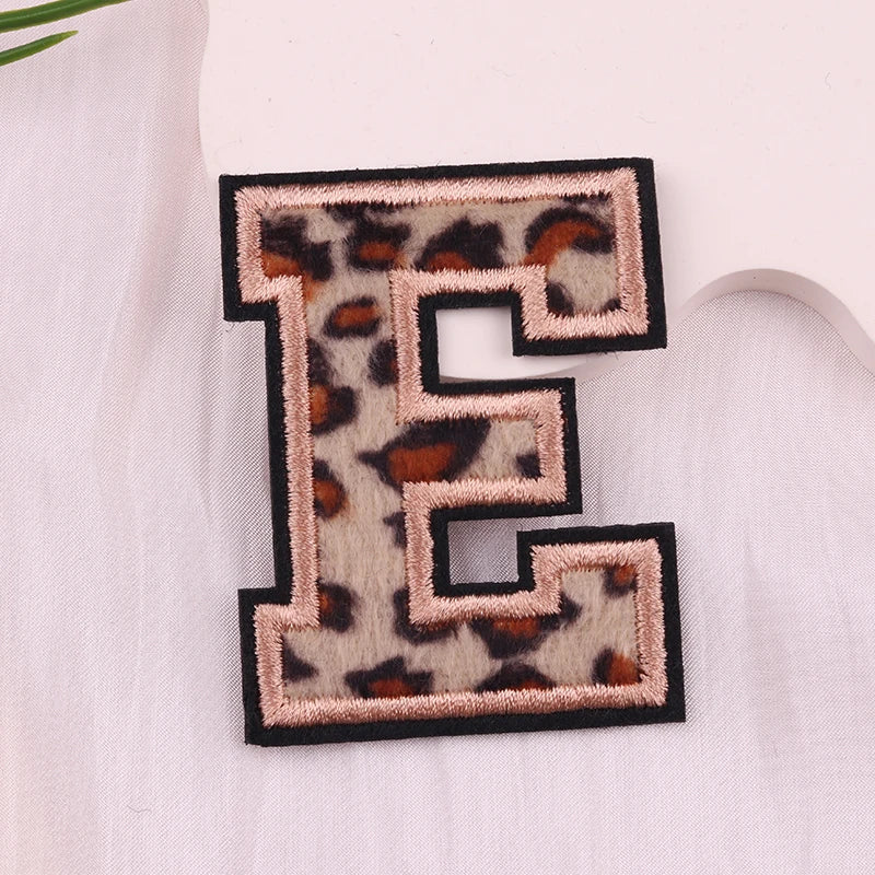 Leopard print letter 'E' patch on a light fabric background