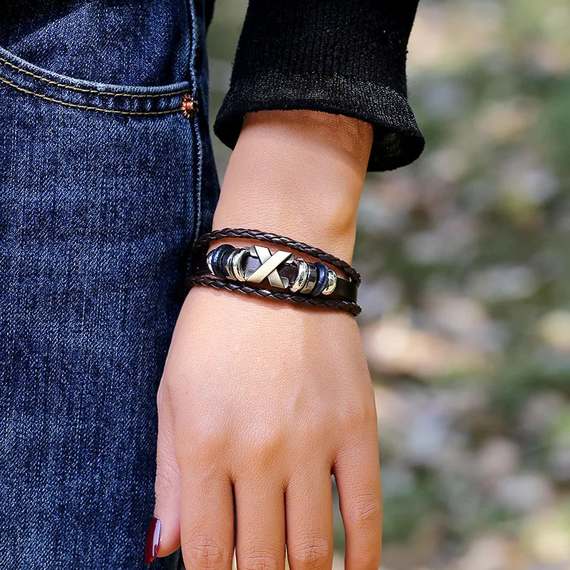 Hand wearing multiple bracelets with a blurred natural background