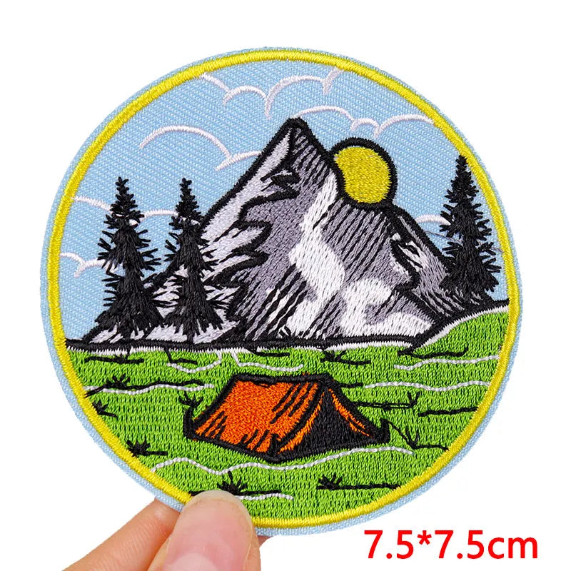 Embroidered patch with mountain and tent design held by a hand, size 7.5*7.5cm.