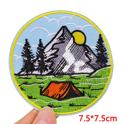 Embroidered patch with mountain and tent design held by a hand, size 7.5*7.5cm.
