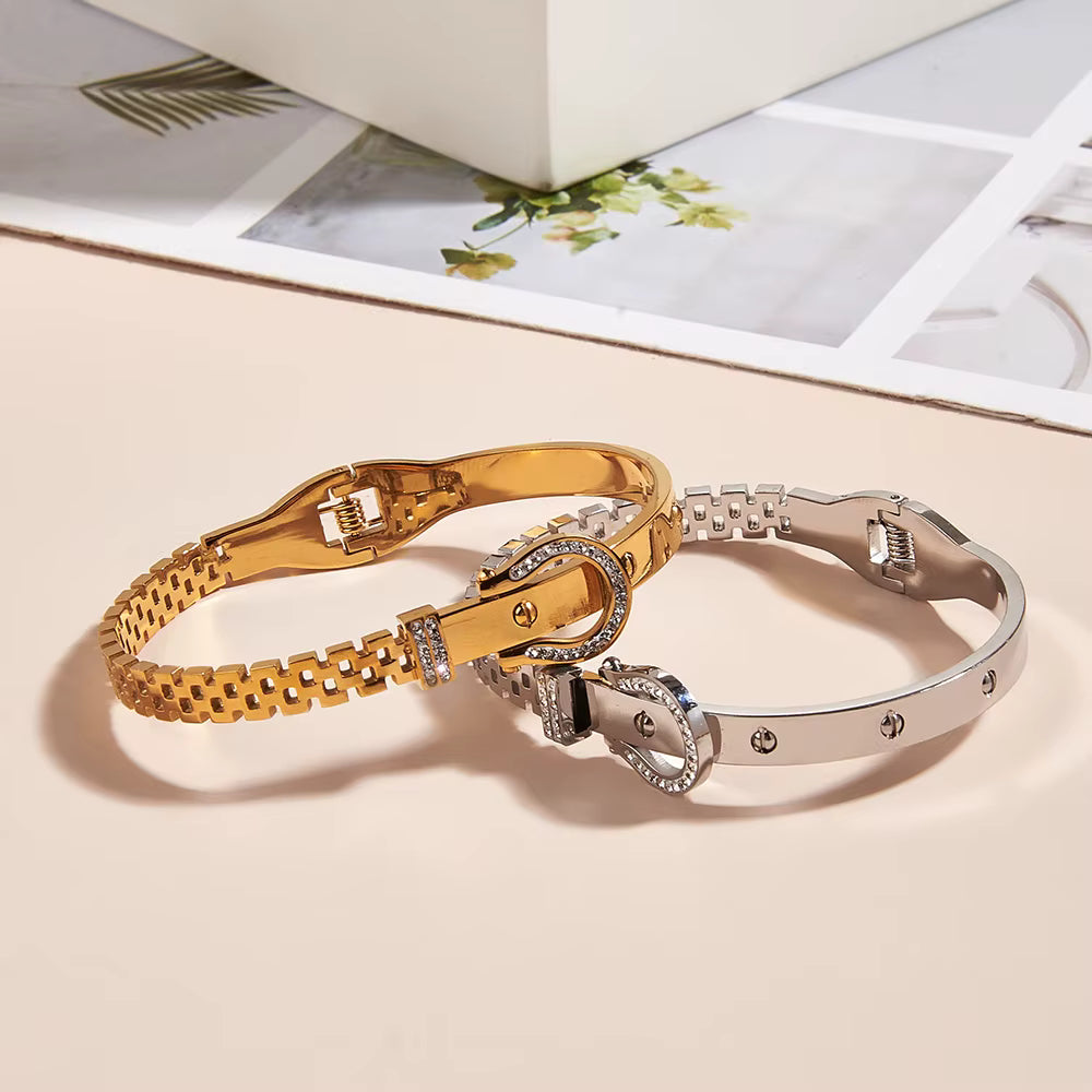 Gold and silver bracelets on a light beige surface with a magazine in the background