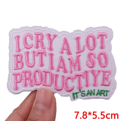 Embroidered patch with pink text held by a hand on a white background