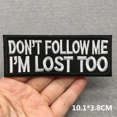 Embroidered patch with 'Don't follow me I'm lost too' text held in hand on gray background