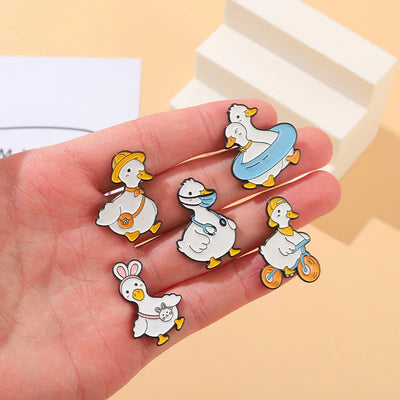 Set of cartoon duck pins on a hand with a beige background