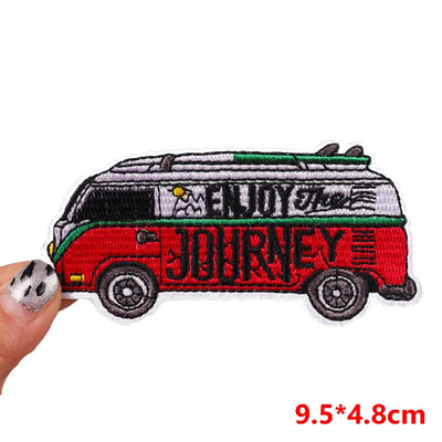 Embroidered patch of a van with 'Enjoy the Journey' text held by a hand.