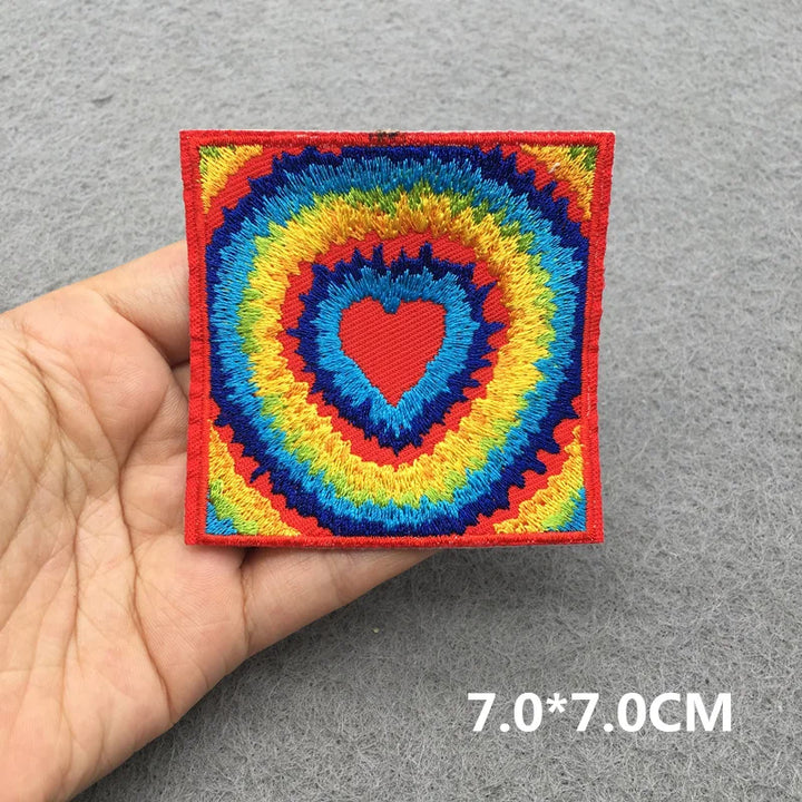 Colorful embroidered patch with a heart design held by a hand on a gray background