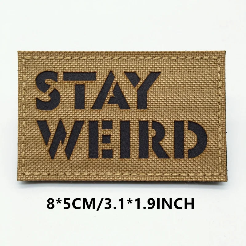Rectangular patch with 'STAY WEIRD' text on a brown background