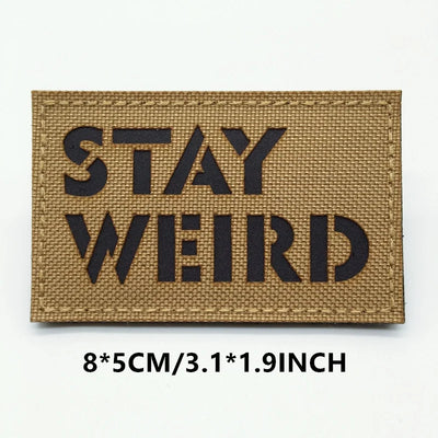 Rectangular patch with 'STAY WEIRD' text on a brown background
