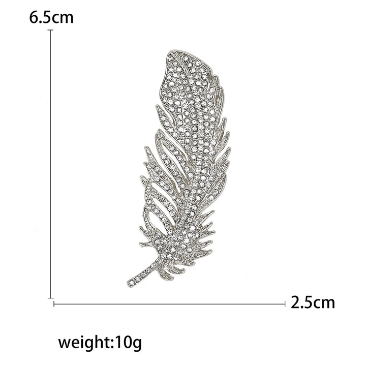 Feather-shaped brooch with gems and measurements and weight on a white background