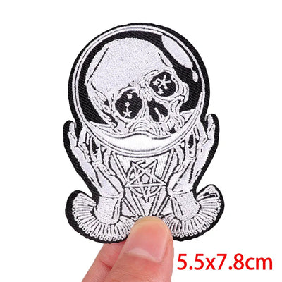 Skull-shaped patch held by a hand with dimensions indicated