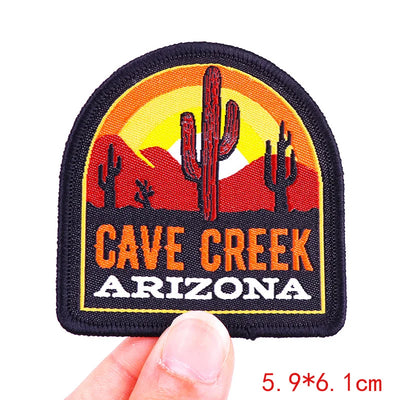 Patch with 'Cave Creek, Arizona' text and desert design held by a hand.