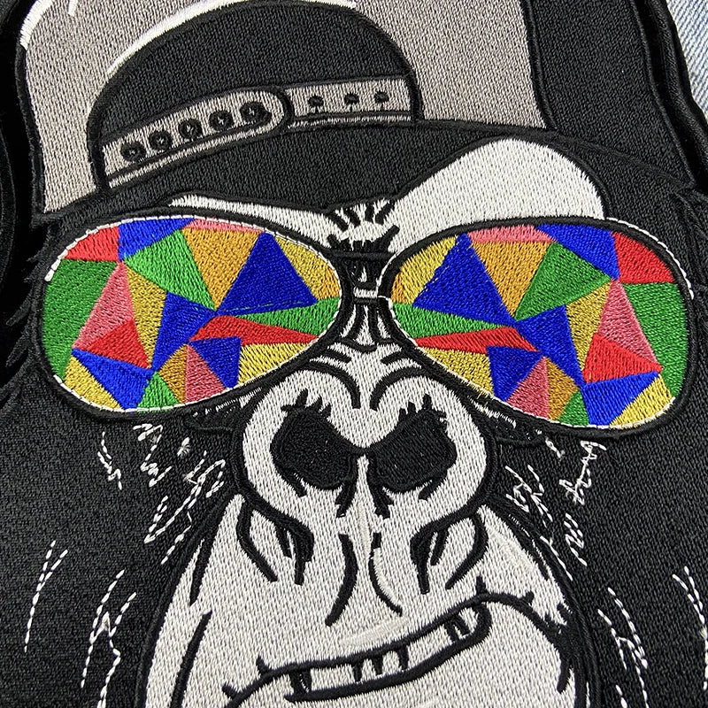 Embroidered patch of a skeleton wearing colorful sunglasses and a cap on a black background