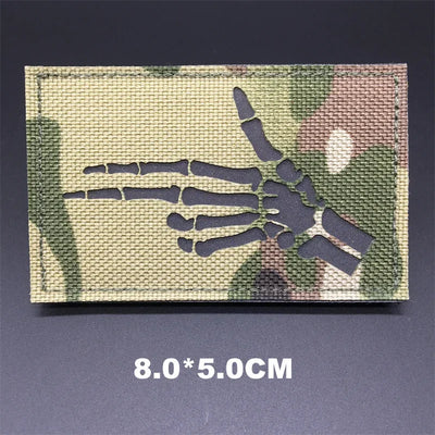 Multicam patterned patch with skeleton hand design on a dark background