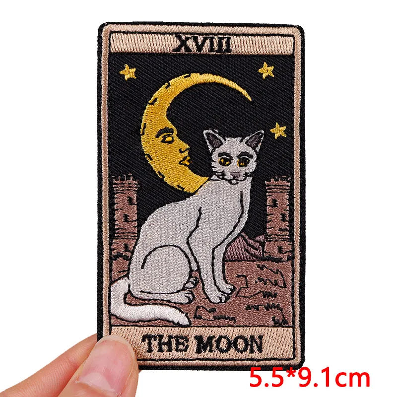 Embroidered patch with a cat and moon design, held by a hand.