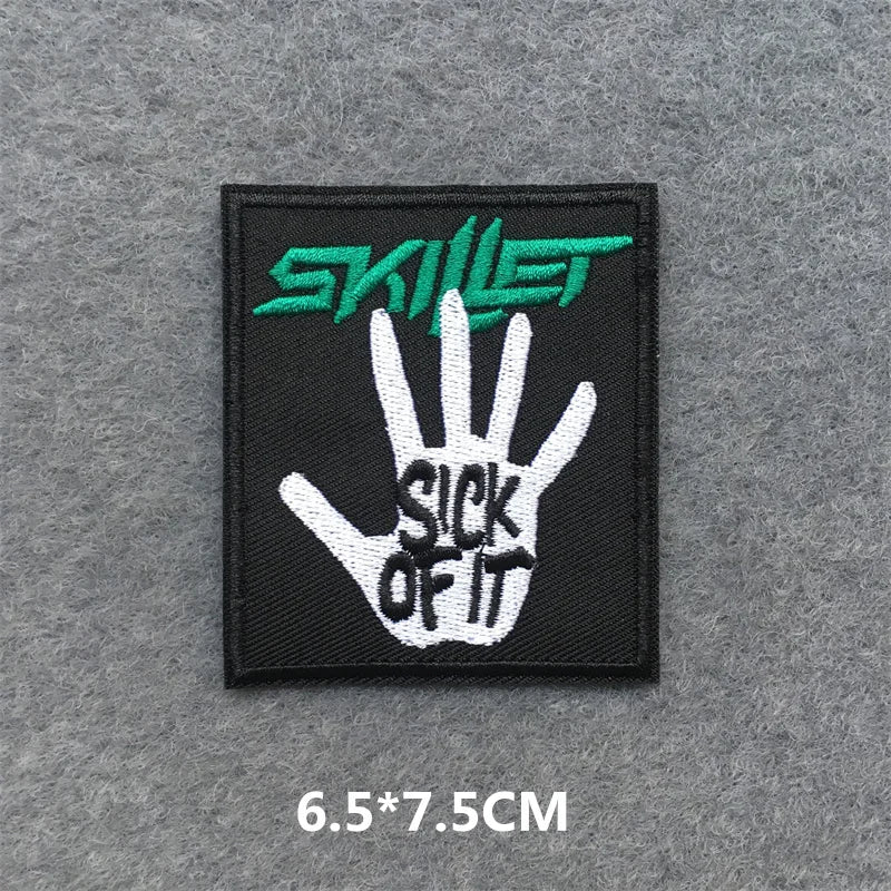 Embroidered patch with 'Skillet' logo and hand design on a gray background