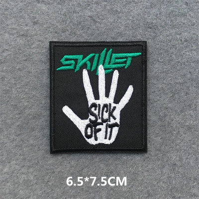 Embroidered patch with 'Skillet' logo and hand design on a gray background