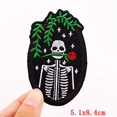 Embroidered patch with skeleton and rose design held by a hand on a white background