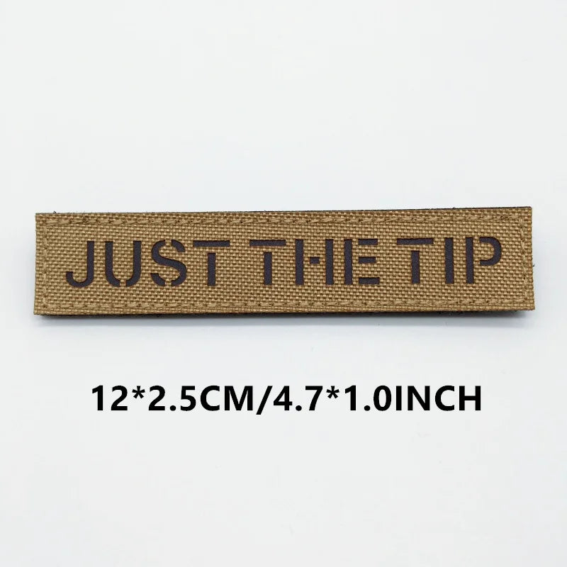 Brown woven label with 'JUST THE TIP' text on a white background