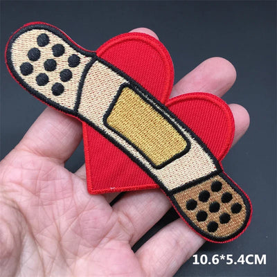 Heart-shaped bandage patch held in a hand with a dark background