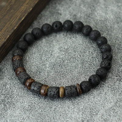 Black beaded bracelet with brown and gold accents on a textured surface