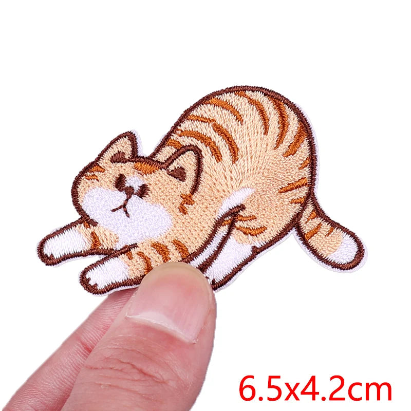 Cat-shaped patch held between fingers with size label '6.5x4.2cm' on a white background