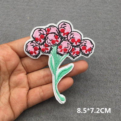 Floral patch held in a hand with dimensions displayed on a gray background