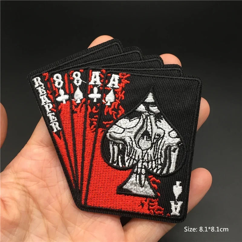 Embroidered patch of aces held in a hand with a dark background