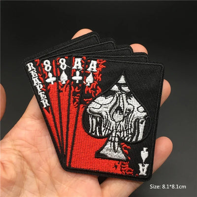 Embroidered patch of aces held in a hand with a dark background