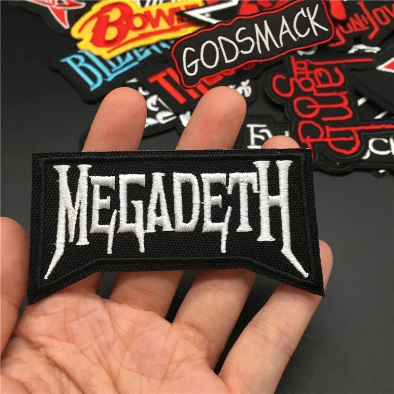 Hand holding a 'MEGADETH' patch with other patches in the background.