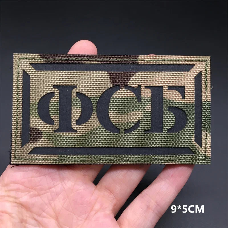 Rectangular patch with text held by a hand against a dark background