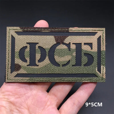 Rectangular patch with text held by a hand against a dark background