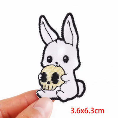White rabbit patch holding a skull with a hand holding it on a white background