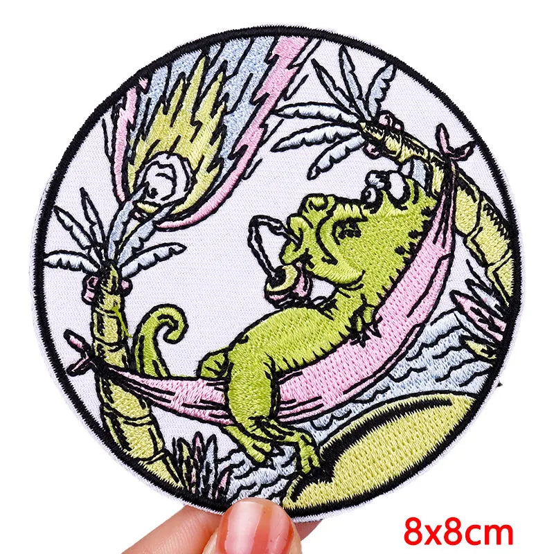Circular patch with a green dragon design held by a hand, with &