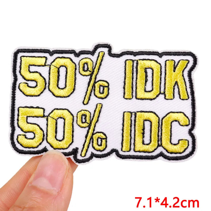 Embroidered patch with '50% IDK, 50% IDC' text held by a hand on a white background.