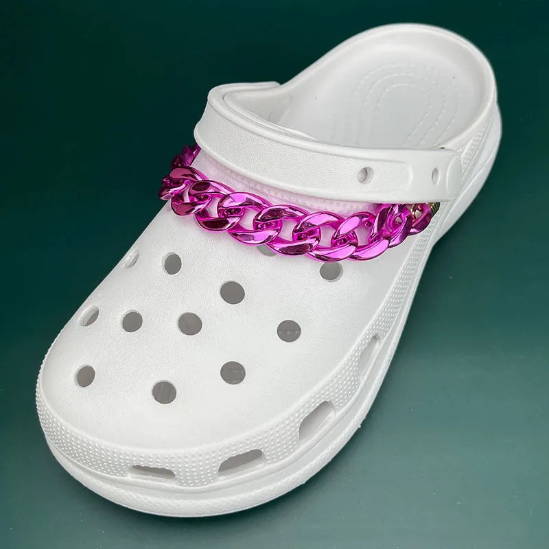 White clog shoe with a pink chain around the ankle on a green background
