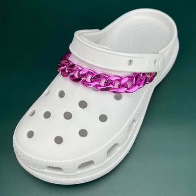 White clog shoe with a pink chain around the ankle on a green background