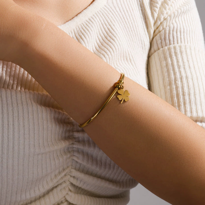Gold bracelet with a clover charm on a person&