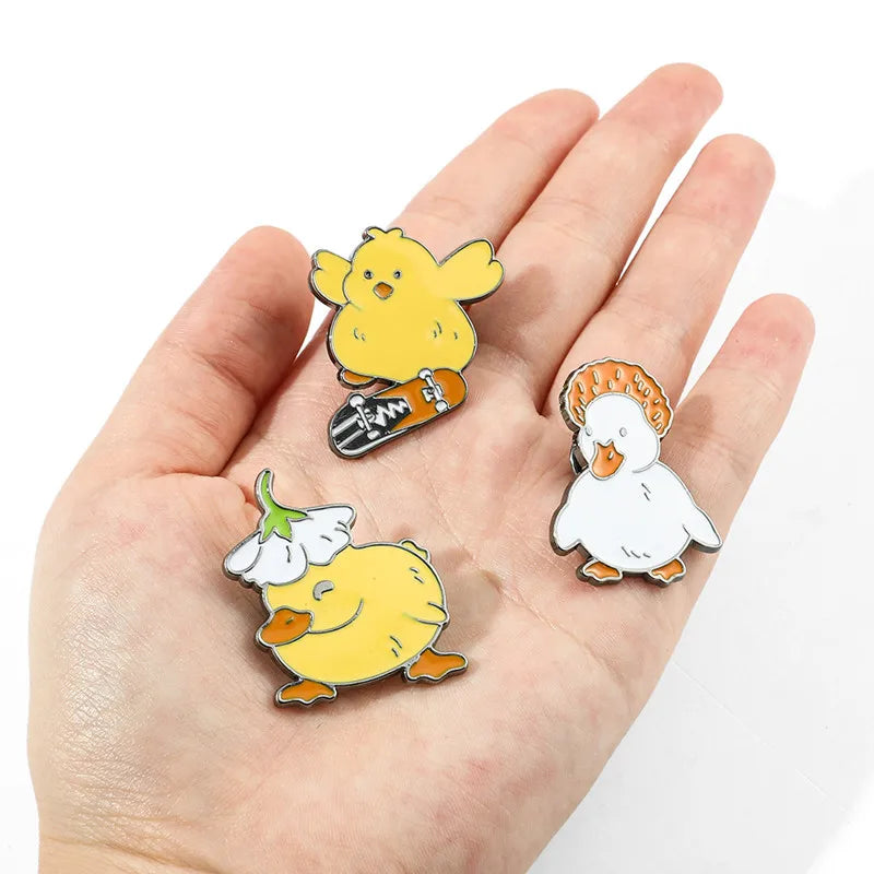 Three cartoon-style pins of a duck, a chick, and a flower held in a hand against a white background.