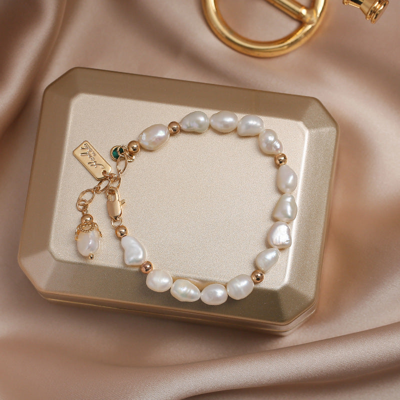 Pearl bracelet with gold accents on a decorative box against a beige fabric background