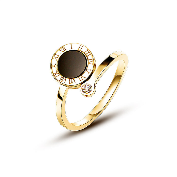Gold tone ring with a dark gemstone and Roman numeral design on a white background