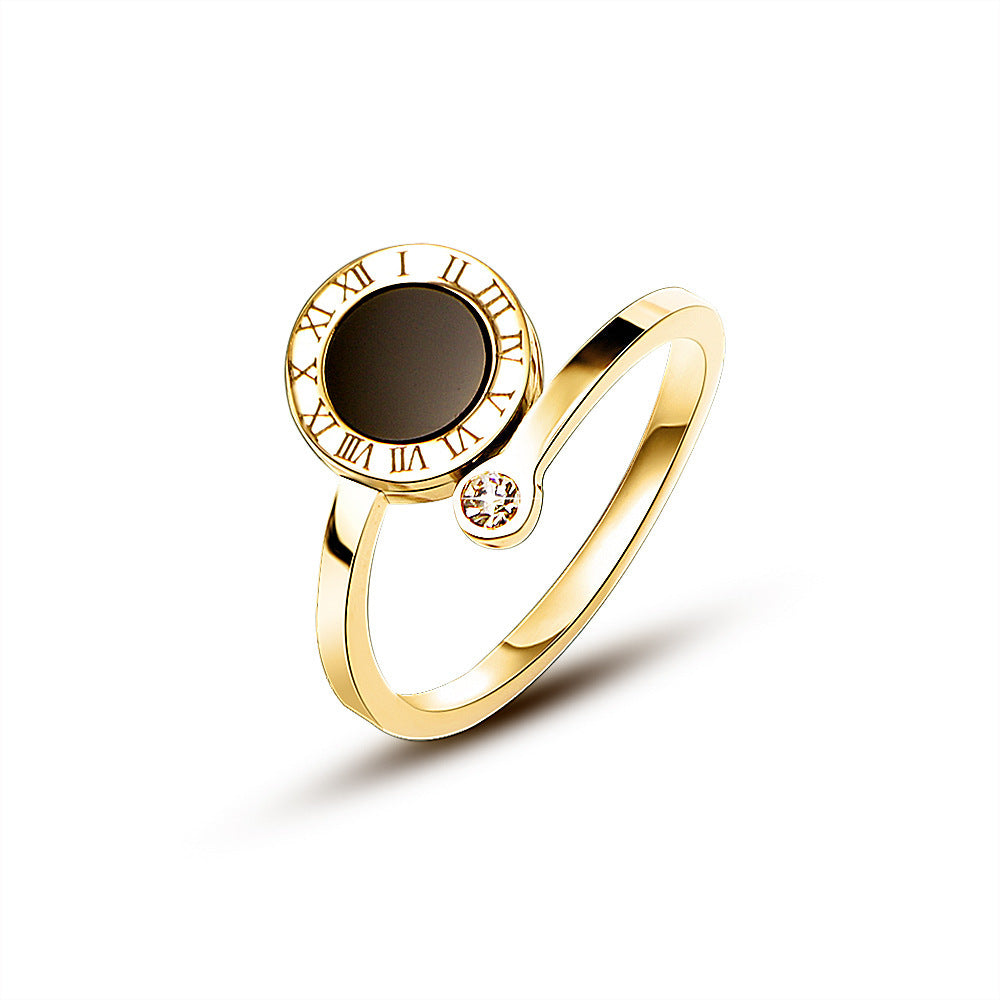 Gold tone ring with a dark gemstone and Roman numeral design on a white background