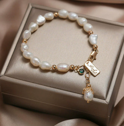 Pearl bracelet with gold accents and a tag on a beige jewelry box
