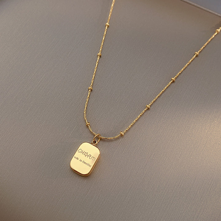 Gold necklace with a pendant on a gray background
