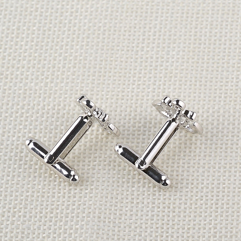 Pair of silver anchor-shaped earrings on a light fabric background