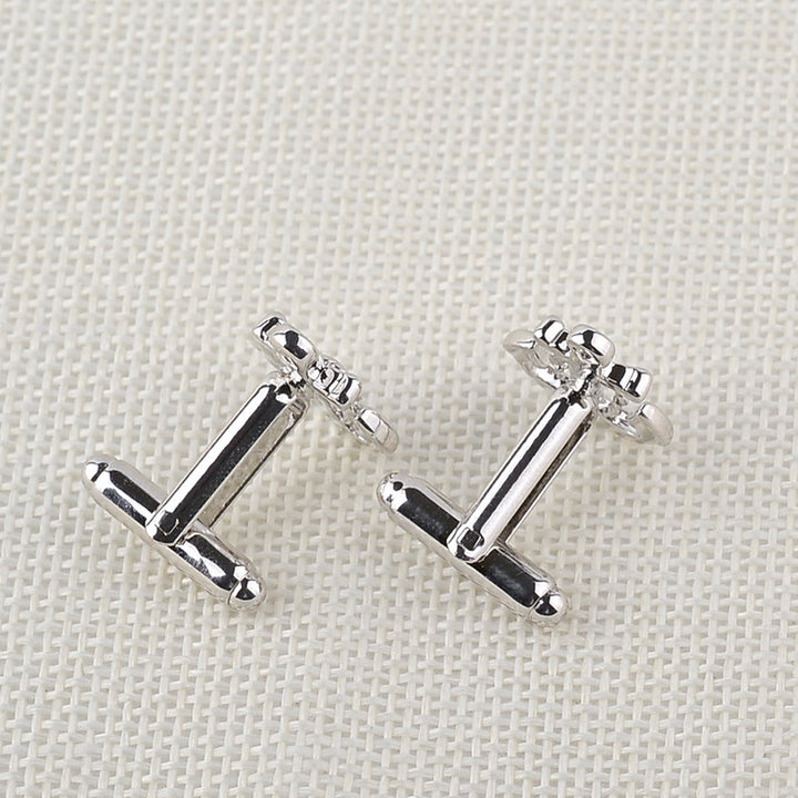 Pair of silver anchor-shaped earrings on a light fabric background