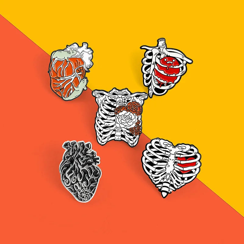 Five anatomical heart and ribcage pins on a two-tone orange and yellow background